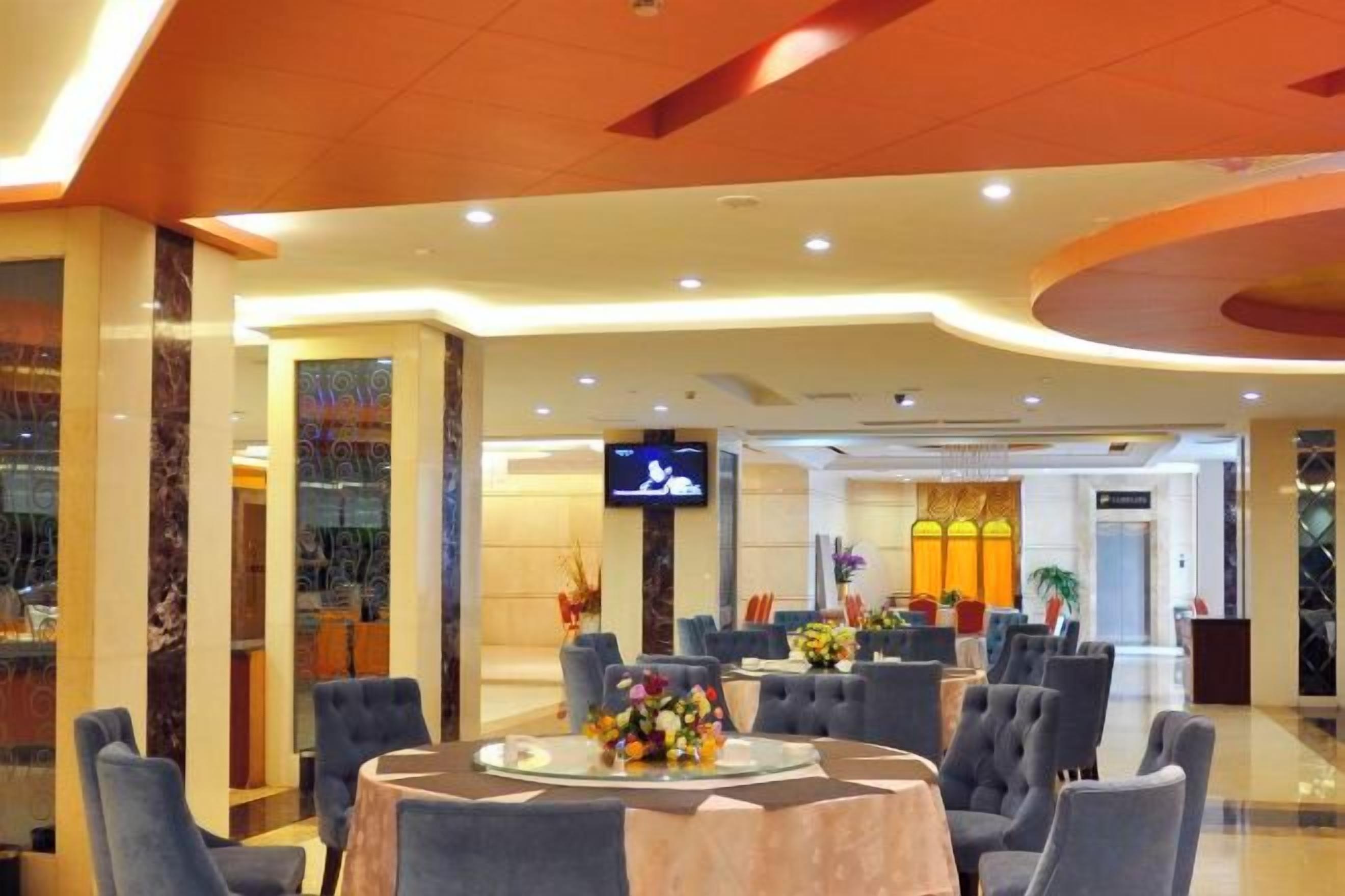 Un vestíbulo de hotel con una mesa redonda, asientos y una pantalla de televisión.