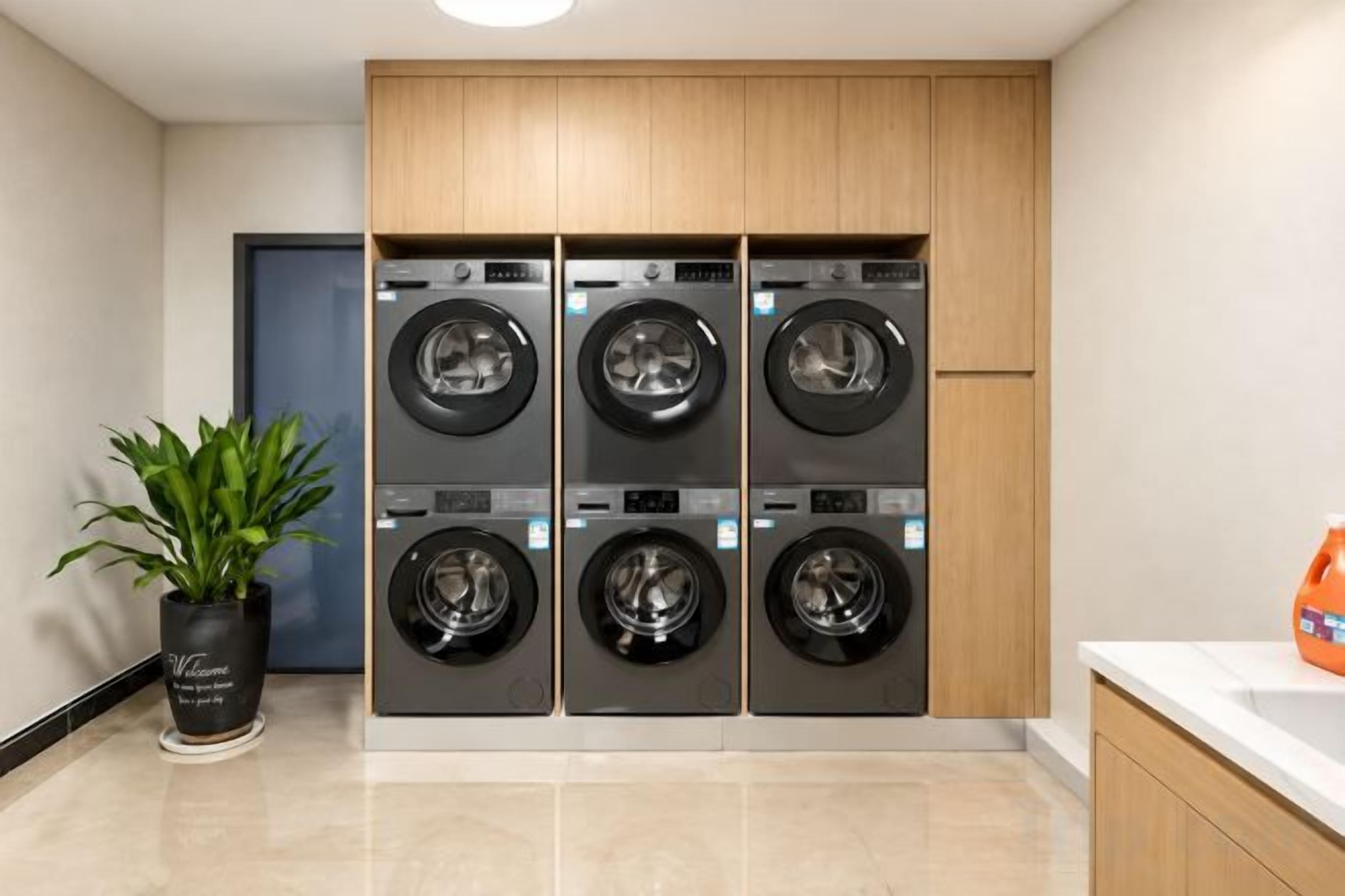 A laundry area with four stacked washing machines, a potted plant, and a sink.