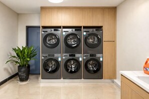A laundry area with four stacked washing machines, a potted plant, and a sink.