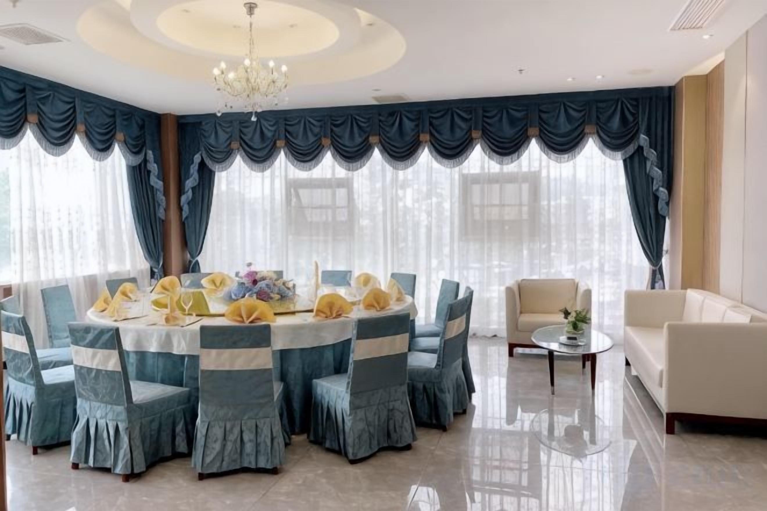 A round dining table with chairs, a chandelier, and curtains.