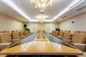 Un salón de conferencias con una larga mesa, varias sillas y una araña.