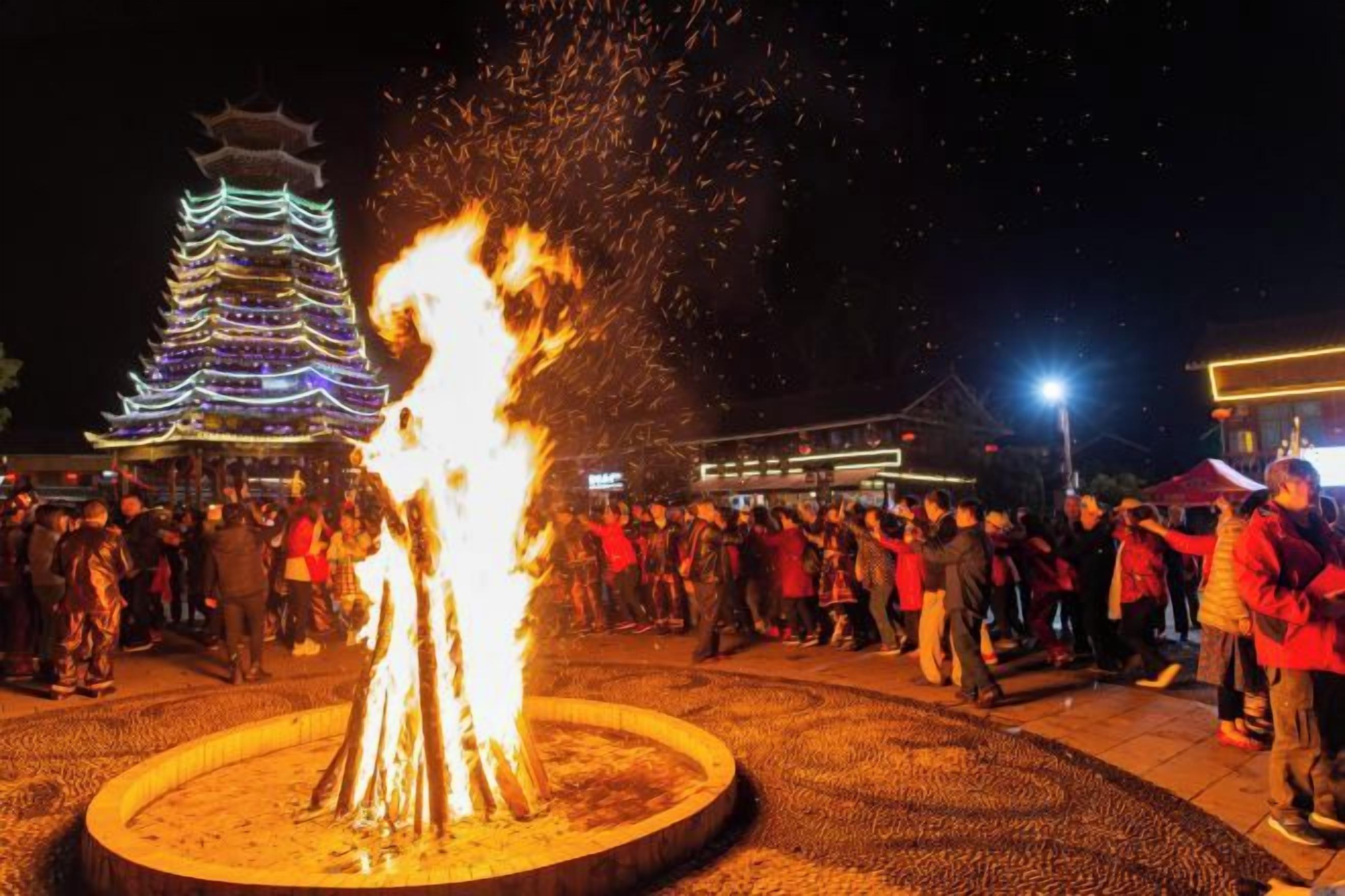 A traditional pagoda-style building with a crowd of people around a central fire feature.