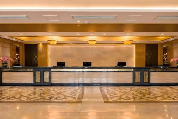 A reception area with a marble counter, two receptionists, and a patterned floor.
