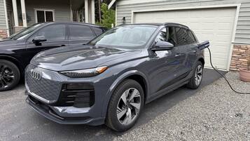 A dark-colored SUV parked in a driveway with a garage in the background.