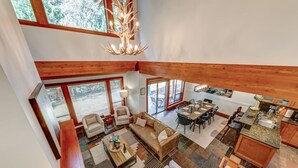 A spacious living area with a high ceiling, a dining table set for four, and a kitchen with granite countertops. - Large 3BD Village Townhome (Whistler)
