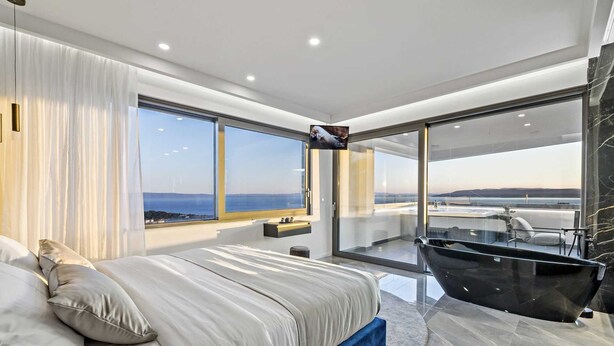 A modern bedroom with a large bed, a bathtub, and a balcony with a sea view. - Villa Mosaicus with Pool (Makarska)