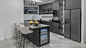 A modern kitchen with a central island, bar stools, a built-in wine cooler, and a refrigerator. - Villa Mosaicus with Pool (Makarska)