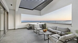 A modern balcony with a view of the sea, a hot tub, and a seating area with cushions and a fruit bowl. - Villa Mosaicus with Pool (Makarska)