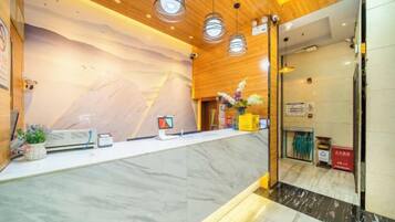 Zona de recepción con mostrador de mármol, techo de madera y decoración con motivos de montaña.