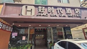 Entrada d'hotel amb un cartell que diu 'HAO SHI DAI HOTEL' i una furgoneta blanca aparcada al davant.