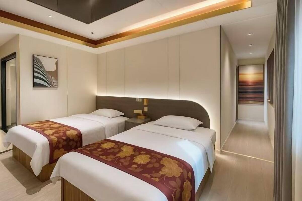 A hotel room with two beds, a modern design, and a hallway with a view.