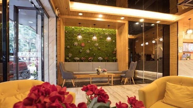 En modern inredning med en sittgrupp, en grön vägg med blommönster och ett träpanelat tak.