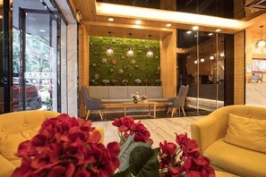 A modern interior with a seating area, a green wall with floral patterns, and a wooden ceiling. - Haoshidai Hotel (Nanning Jiangnan Passenger Station Jinxiang Avenue Subway Station) (Nanning)