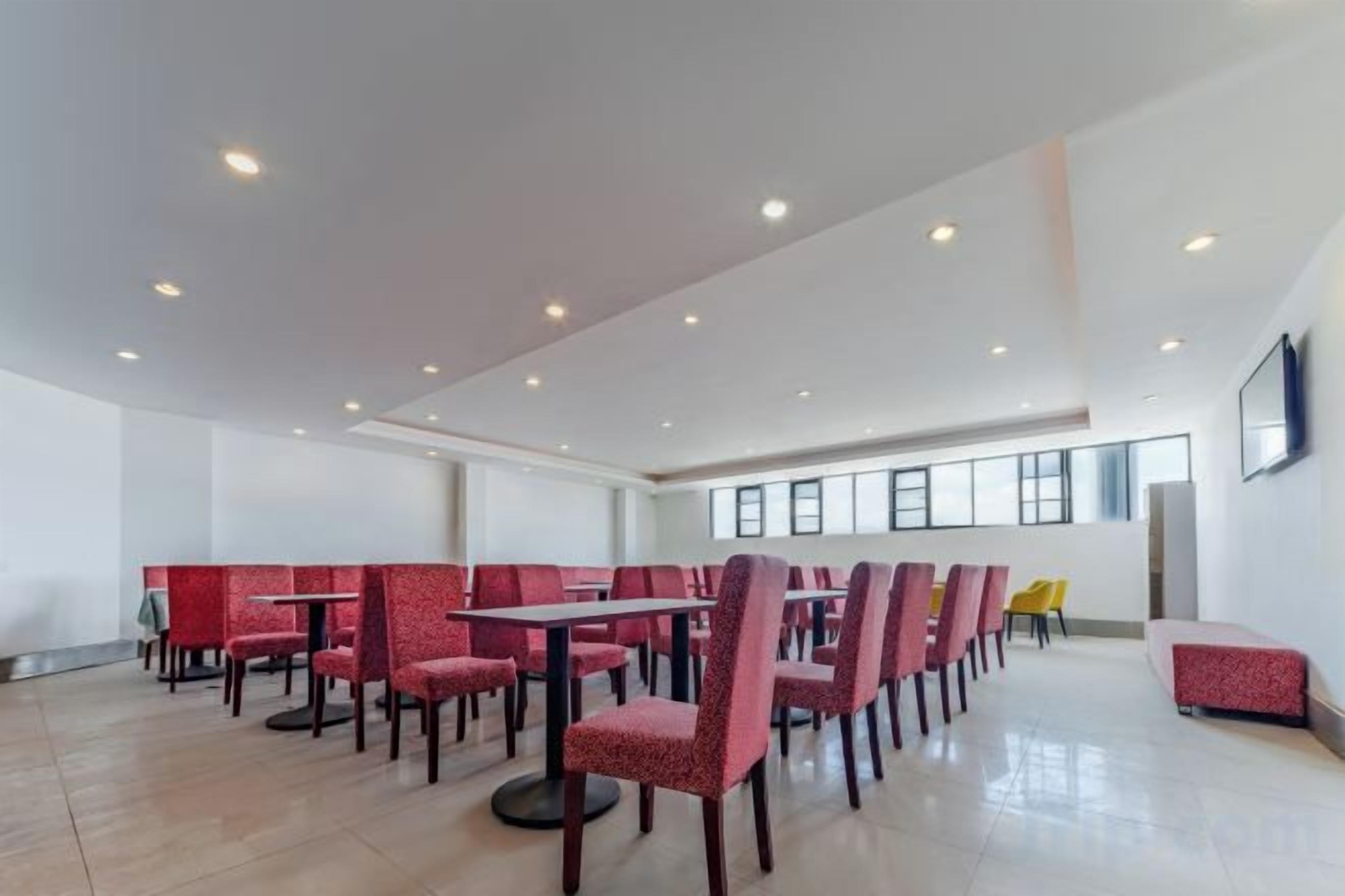 A spacious indoor area with multiple tables and chairs, high ceilings, and large windows.