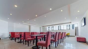 A spacious indoor area with multiple tables and chairs, high ceilings, and large windows.