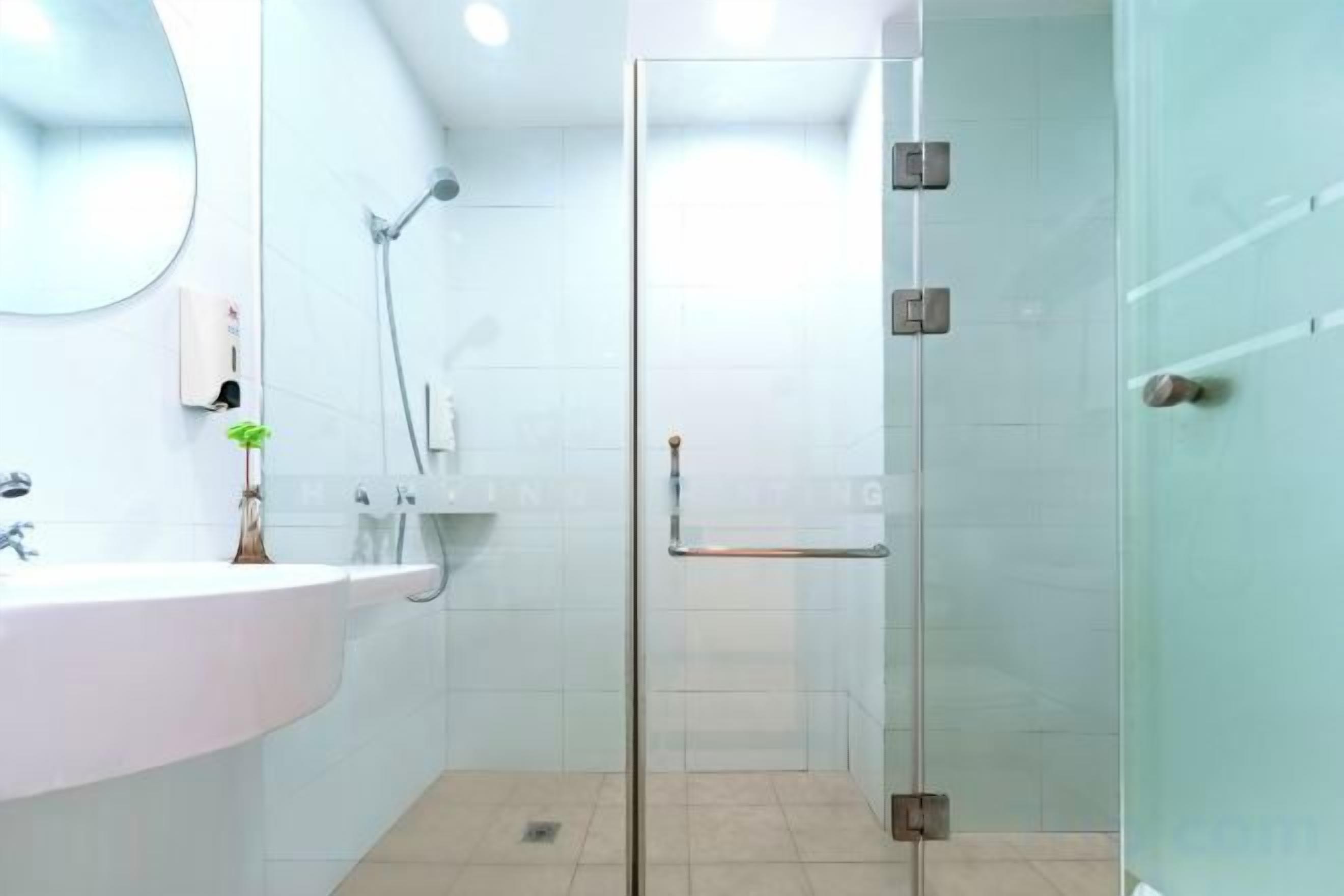 Un baño con cabina de ducha de vidrio, un lavamanos blanco y un espejo.