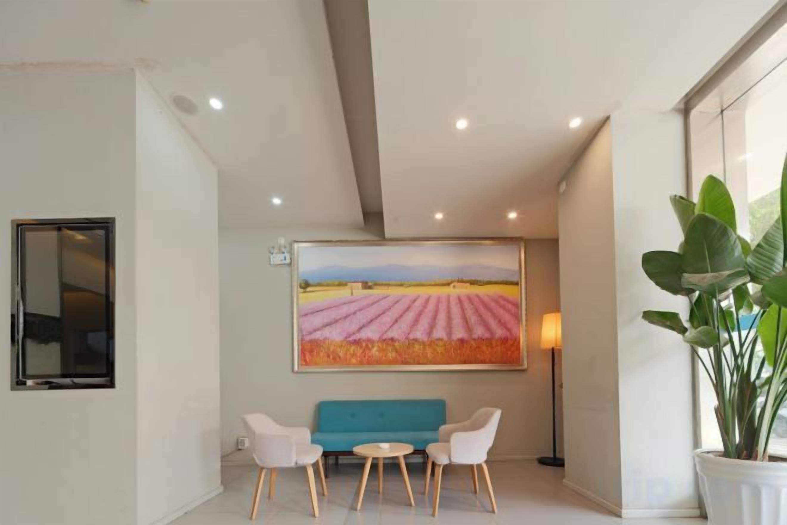 Un intérieur moderne avec un canapé et des fauteuils, un grand tableau et une plante en pot.