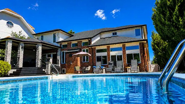 A swimming pool with lounge chairs and a covered patio area.