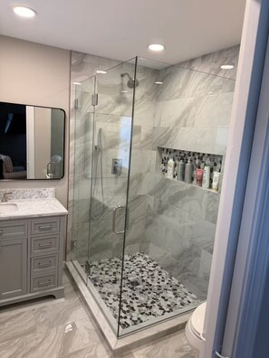 A modern bathroom with a glass-enclosed shower, marble flooring, and a vanity with a mirror. - Riverfront House in Kilmarnock-Perfect for the whole Family (Kilmarnock)