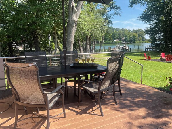 An outdoor patio with a table and chairs, overlooking a lake. - Riverfront House in Kilmarnock-Perfect for the whole Family (Kilmarnock)