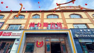 A building with multiple storefronts, including one with a prominent red sign.