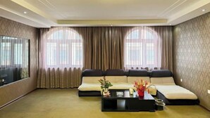 A living room with a sofa, a coffee table, and a TV. - Wanliyuan Hotel (Fuyuan)