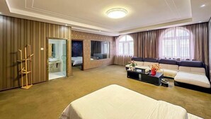 A hotel room with a bed, a sofa, a coffee table, a mirror, and a wardrobe. - Wanliyuan Hotel (Fuyuan)