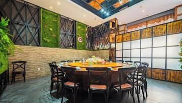 A conference room with a round table, multiple chairs, and a green wall with plants.