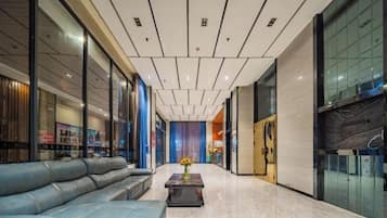 A hotel lobby with a modern design, featuring a leather sofa, a coffee table, and a glass wall.