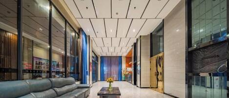 Un hall d’hôtel au design moderne, avec un canapé en cuir, une table basse et un mur en verre.