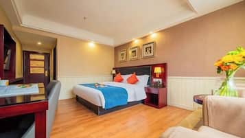 Una habitación de hotel con cama, mesitas de noche, escritorio y silla.