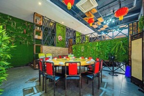 A restaurant with a round table and chairs, a green wall with plants, and red lanterns. - Tiancheng Business Hotel (Pingxiang Railway Station) (Pingxiang)
