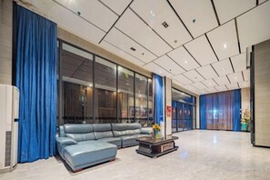 Eine moderne Lobby mit einer Ledersofa, einem Couchtisch und einem großen Fenster mit Vorhängen.