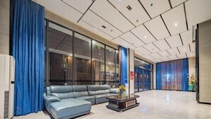A modern lobby with a leather sofa, a coffee table, and blue curtains. - Tiancheng Business Hotel (Pingxiang Railway Station) (Pingxiang)