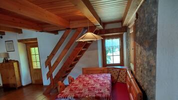 Une pièce rustique avec une table, un banc et un escalier en bois.