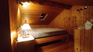 Una habitación pequeña y acogedora con una cama individual, una mesita de noche con lámpara y un armario de madera.