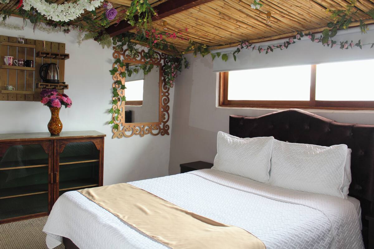 A bedroom with a bed, wooden dresser, and a mirror.