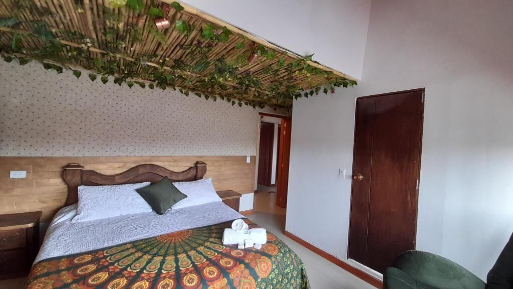 A hotel room with a bed, a wooden headboard, a patterned bedspread, and a door.