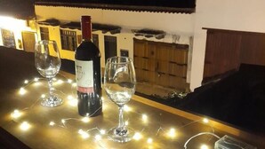 A bottle of wine and two glasses on a table with string lights. - Vivelavilla suites VDL (Villa de Leyva)
