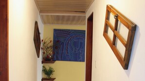 A hallway with a wooden door, a wall-mounted picture frame, and a blue abstract painting. - Vivelavilla suites VDL (Villa de Leyva)