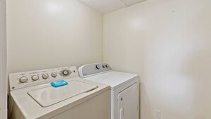 A compact laundry room with a washing machine and dryer, a control panel with multiple dials, and a blue cloth on the washing machine.