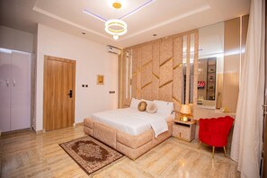 Une chambre à coucher avec un lit, une table de chevet, un fauteuil rouge, un miroir et un luminaire au plafond.