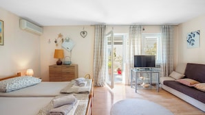 A hotel room with two beds, a sofa, a TV, a small table, and a view of the outside. - Apartment in Brodarica Near Beach & Krka Park (Sibenik)
