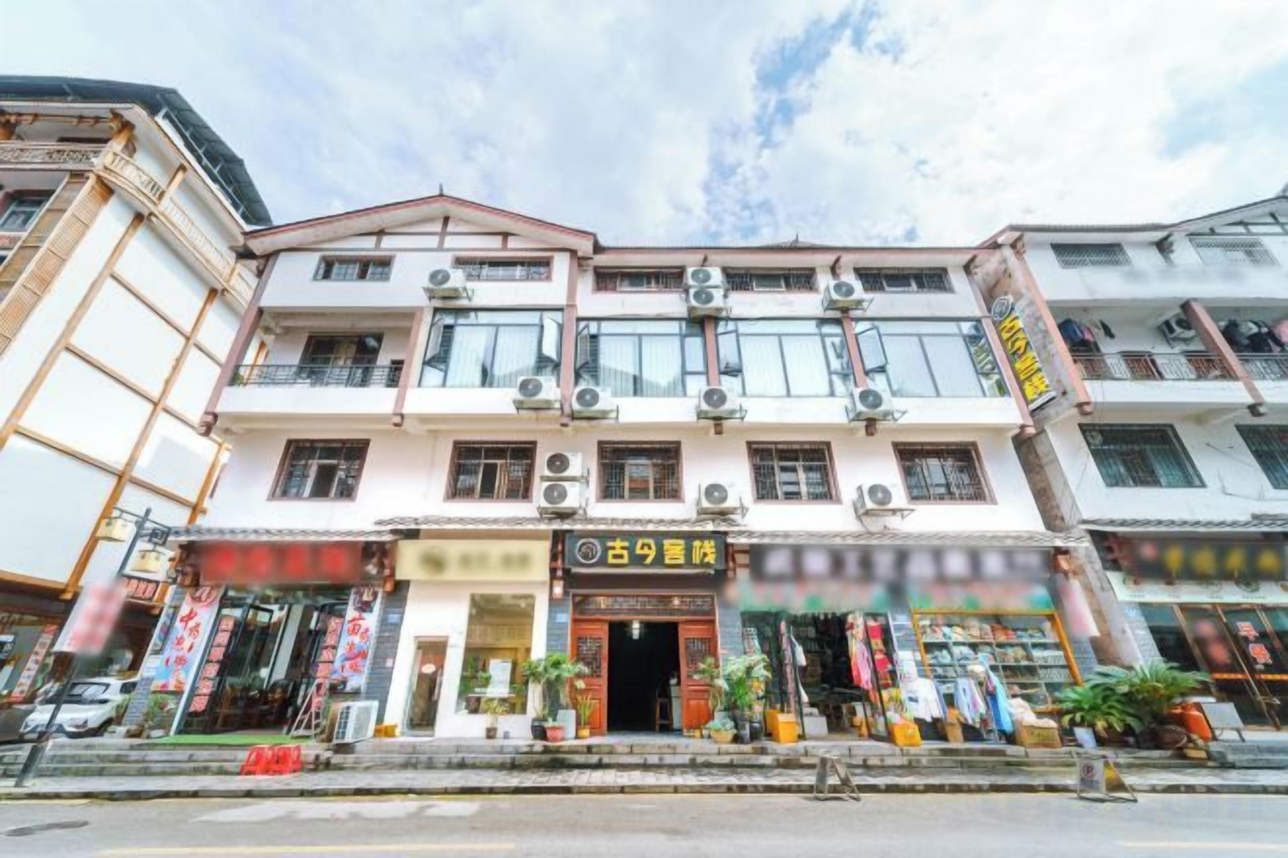 A multi-story building with a traditional architectural style, featuring a central entrance with a signboard, multiple windows, and a visible storefront with merchandise.