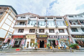 A multi-story building with a traditional architectural style, featuring a central entrance with a signboard, multiple windows, and a visible storefront with merchandise.