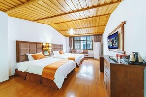 Habitación de hotel con dos camas, techo de madera, televisión y escritorio con hervidor.