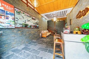 A reception area with a wooden ceiling, stone flooring, a reception desk, and a wall with a bulletin board.