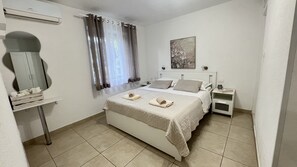 A neatly arranged bedroom with a bed, bedside tables, a mirror, and a window with curtains. - Apartmani Vela Makarska - Studio With Garden View (Makarska)