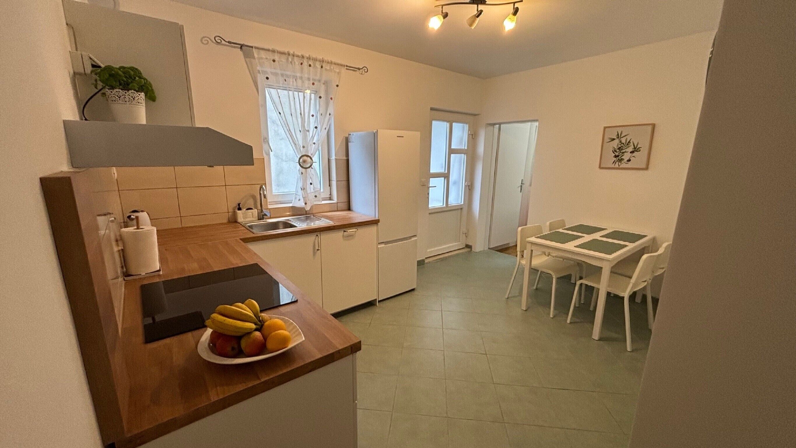 Une cuisine compacte comprenant un évier, un petit réfrigérateur et un coin repas avec une table et des chaises.