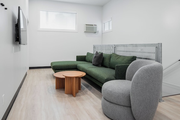 A modern living room with a green sofa, a grey armchair, and a wooden coffee table.